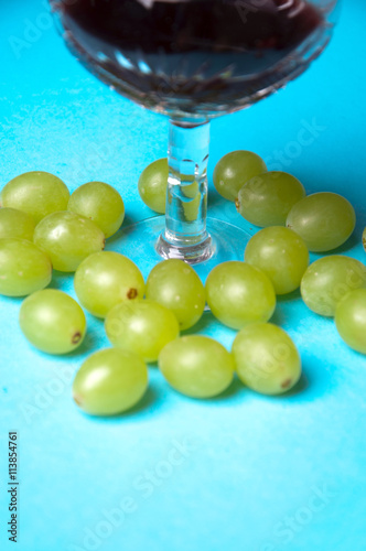 glass of wine and grapes, isolated on blue