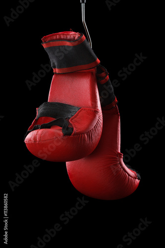 Old boxing gloves hang on nail black background