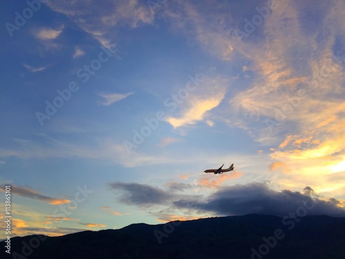 flying airplane over mountain range at sunset