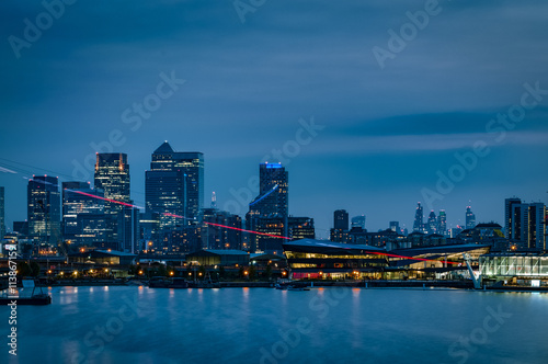 The London skyline at night with the skyscrapers from The City of London ( London’s financial center) and the skyline of Canary Wharf ( Isle of Dogs, Docklands) illuminated