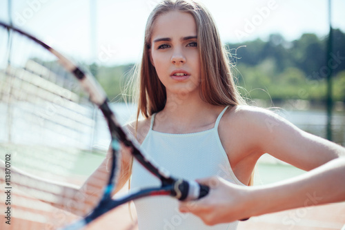 close up portrait of young woman playing tennis holding a racke