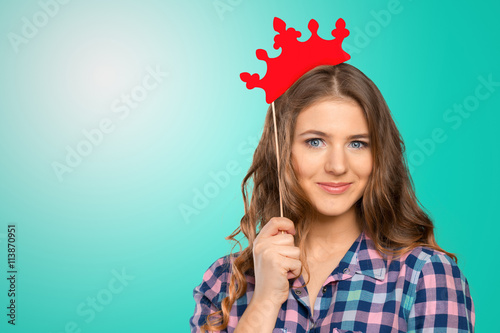 Closeup portrait of beautiful young girl with festive paper crown on her head.