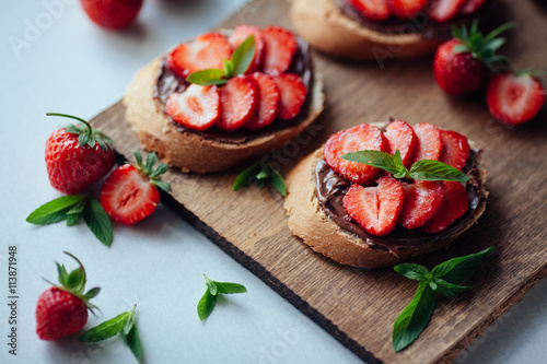 Strawberry bruschetta with chocolate paste and mint.Healthy thre