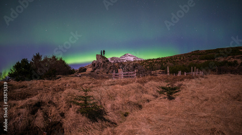 Tourist looking the Aurora boraelis over the sky in Iceland.