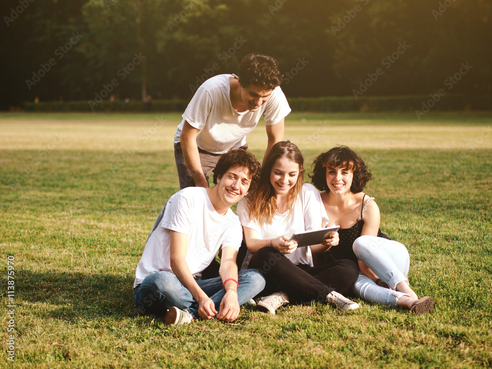 large group of friends together in a park using a tablet large group of friends together in a park using a tablet