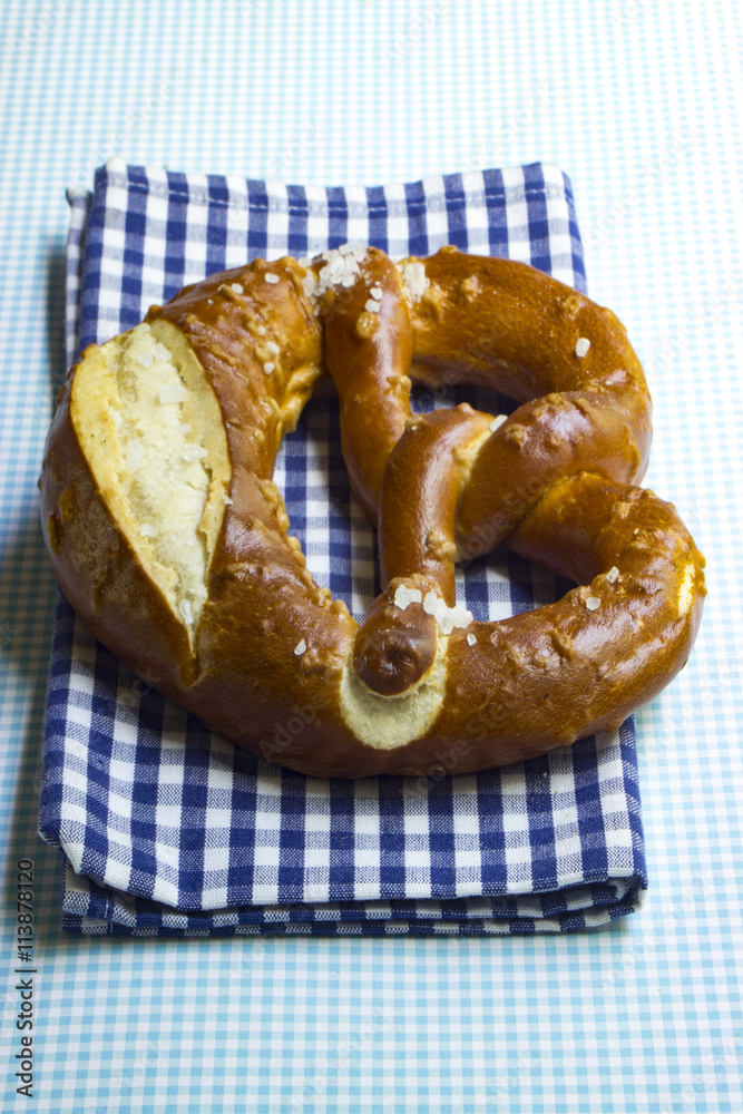 Bayrische Brezel auf weiß-blau karierter Serviette im Hochformat