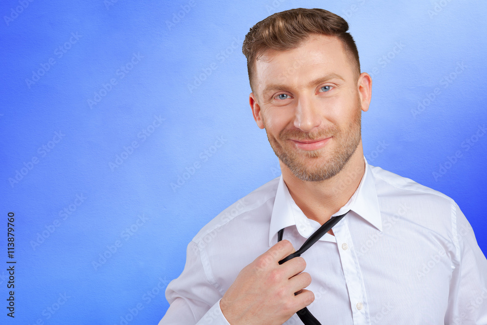 Confident young man in shirt and tie adjusting his necktie Confident young man in shirt and tie adjusting his necktie