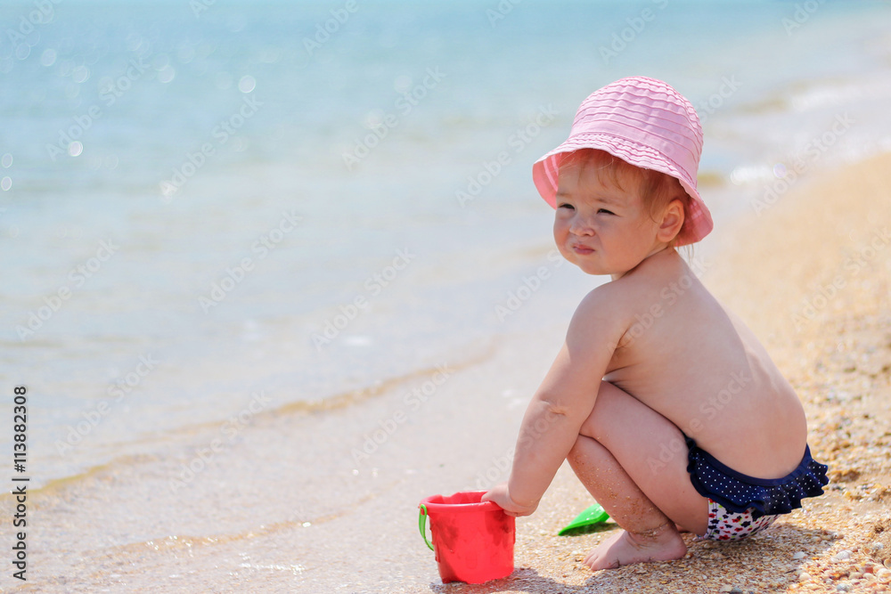 Baby girl playing on the beach near the sea