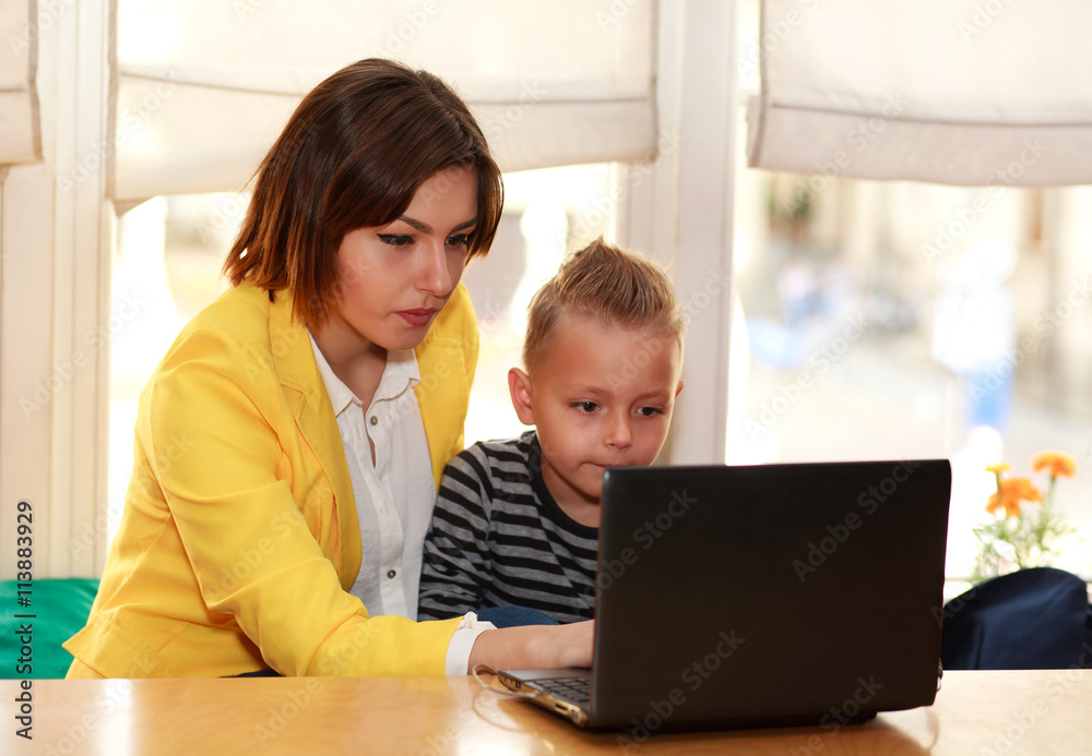 Mother and son at home doing lessons looking at laptop Mother and son at home doing lessons looking at laptop