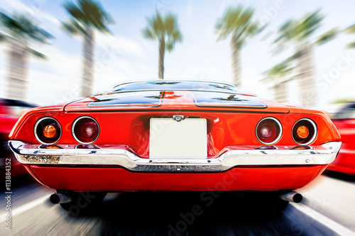 Back view of classic 1972 Chevrolet Camaro in orange color, in motion. Speeding.