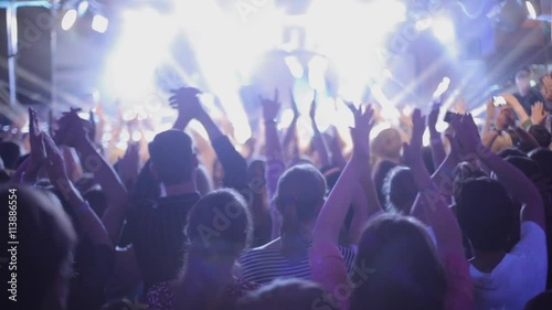 Large group of happy people enjoying rock concert, clapping with raised up hands, lights from the stage 1