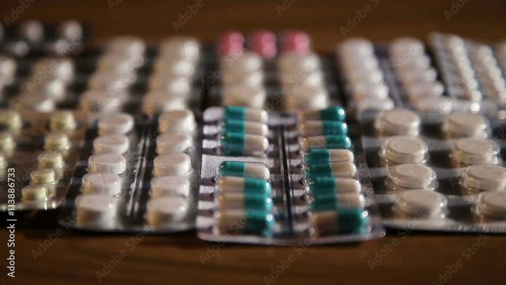 Package of medicine pills for better health.Medicine.Pills and capsules in aluminum container on wooden table.Many various pills lying on the table.Pile of Drugs Closeup. Package of medicine pills for better health.Medicine.Pills and capsules in aluminum container on wooden table.Many various pills lying on the table.Pile of Drugs Closeup.