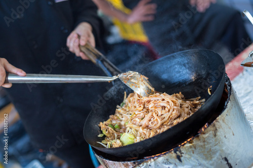 Cheff cooking traditional Thai noodles, Pad Thai, on street stall on international street food festival of Odprta kuhna, Open kitchen event, in Ljubljana, Slovenia. photo