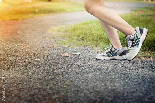 Close up of young woman jogging at the park with sunset.