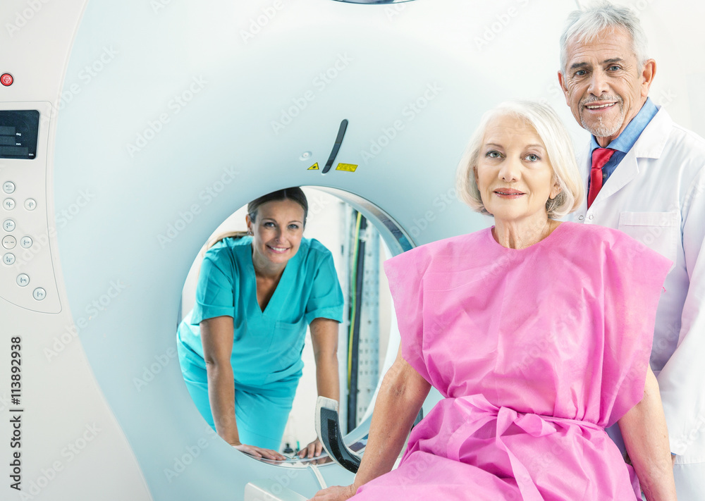 Obraz premium Woman in 60s ready to undergo MRi scan, assisted by two reassuri