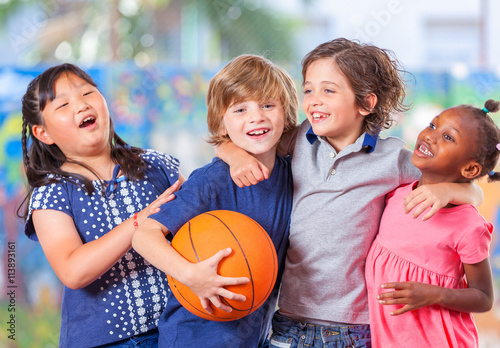 Happy children embracing while playing basketball. Primary schoo photo