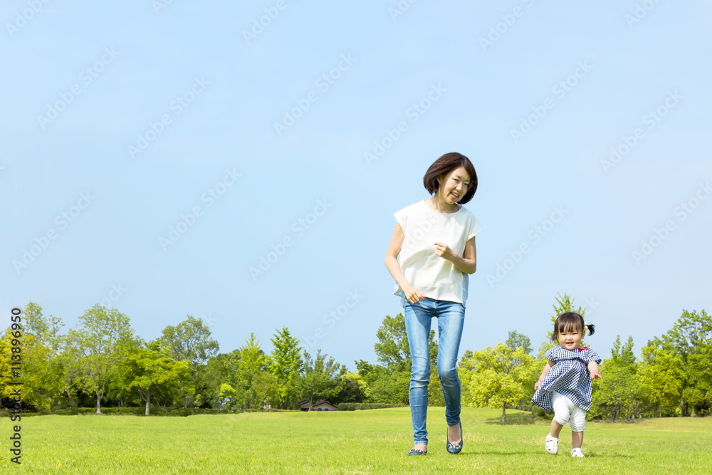 青空の下、芝生の公園で幼い女の子とt走る母子 青空の下、芝生の公園で幼い女の子とt走る母子