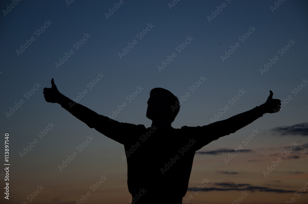 silhouette of man standing in a field at sunset.