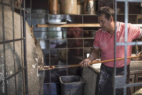 Pizza baker putting pizza in pizza oven