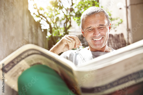 Portrait of smiling man reading newspaper photo