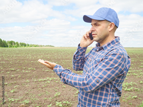 Farmer in a plaid shirt controlled his field.Talking on phone. © volkovslava