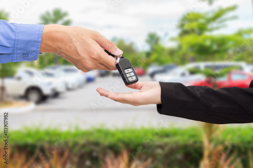 Businesswomen giving a key car to businessman at car parking