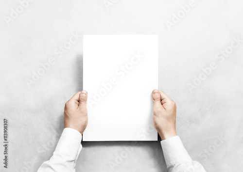 Hand holding white blank paper sheet mockup, isolated. Arm in shirt hold clear brochure template mock up. Leaflet document surface design. Simple pure print display show. Reading contract agreement.