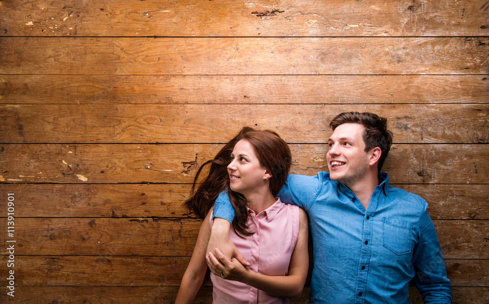 Beautiful young couple hugging against wooden background