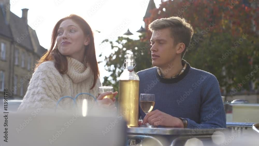 Young couple enjoying a cup of tea together in a cafe. They are sitting outdoors. Young couple enjoying a cup of tea together in a cafe. They are sitting outdoors.