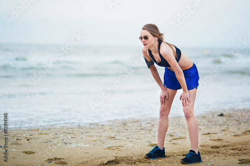 Young fitness running woman jogging on beach