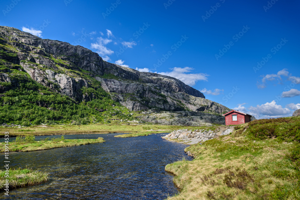Small red cabin on a lake shore in Norway
