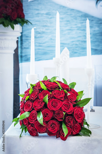 букет из алых роз на столе со свечами