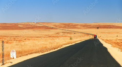 Red truck on the road in the barren landscape of Madagascar