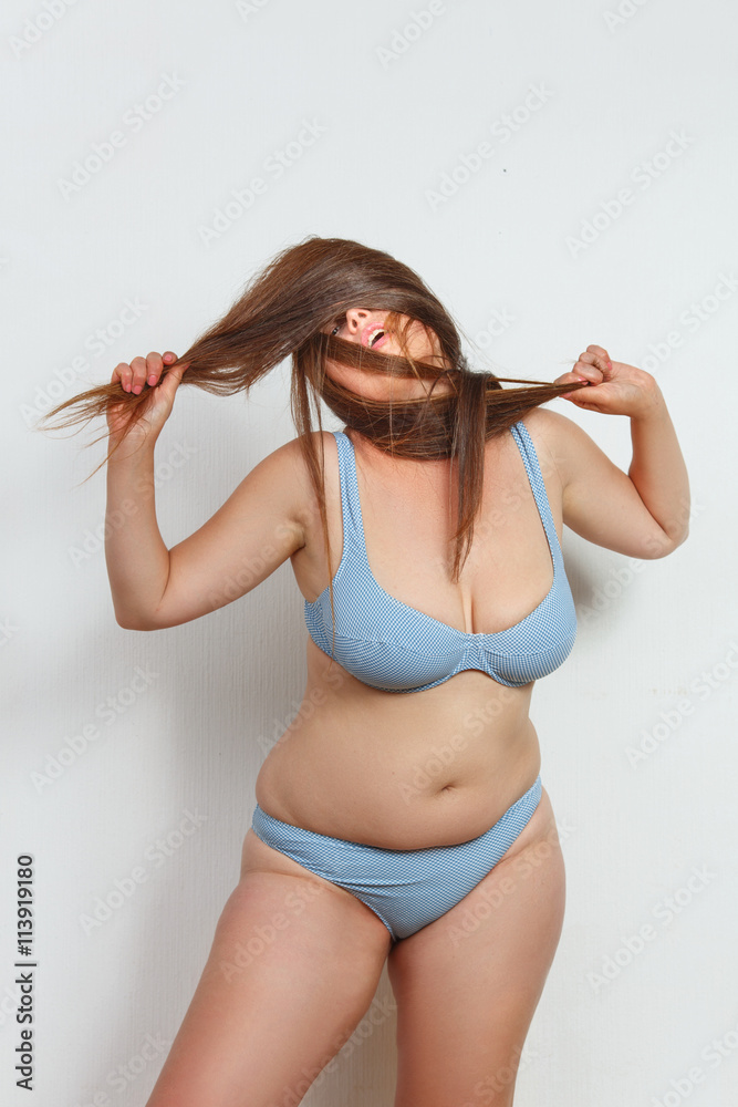 Portrait of beautiful fat woman in underwear or lingerie touching her red  hair while posing for photographer in studio. Stock Photo | Adobe Stock