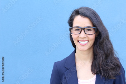Closeup portrait, young professional, beautiful confident adult woman in blue blasier, with black glasses, smiling isolated indoors office background. Positive human emotions