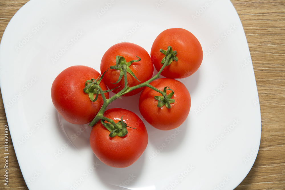 Fresh red tomatoes in white plate on wooden table Fresh red tomatoes in white plate on wooden table