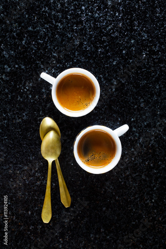 two cups of fresh Coffee Espresso on black Marble and two golden