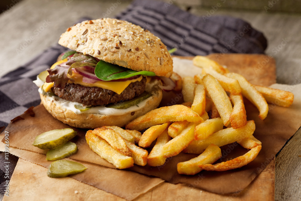 Delicious homemade hamburger with french fries on wooden vintage table Delicious homemade hamburger with french fries on wooden vintage table