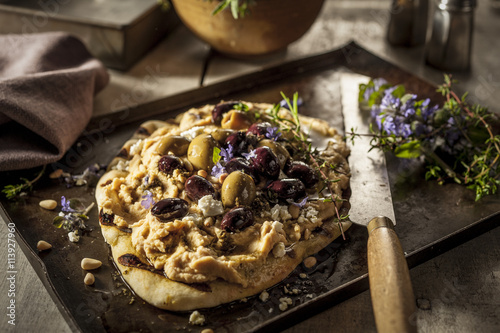 Freshly cooked bread with hummus and olives on tray