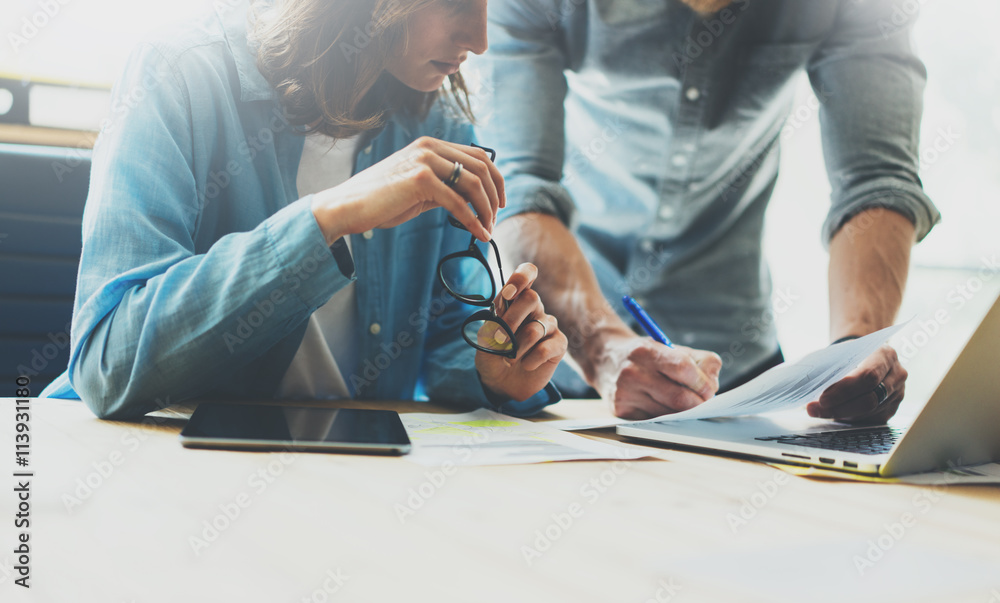 Fototapeta premium Coworking team brainstorming process in modern office.Project manager analyze reports,holding glasses female hand.Young business crew working with startup studio.Laptop wood table.Blurred,film effec