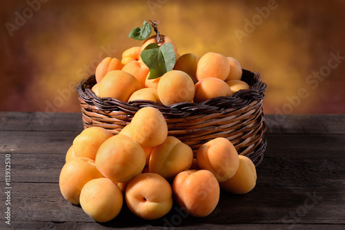 Apricots in the basket and on wooden table 