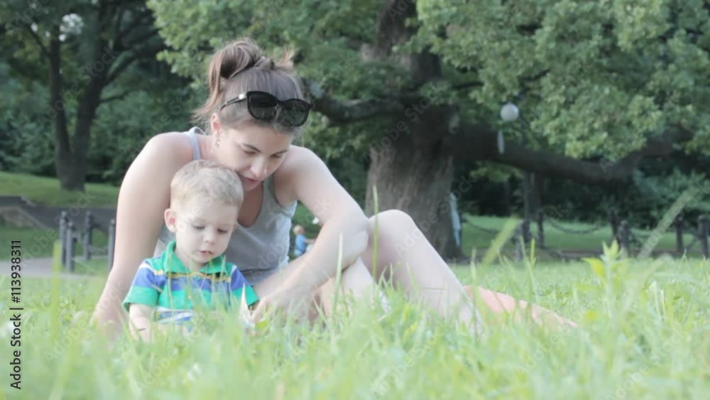Mother with the children in the park reading a book
