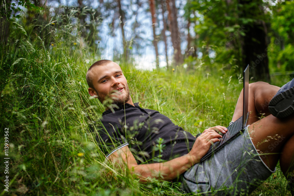 Caucasian male lying on a grass and using laptop. Caucasian male lying on a grass and using laptop.