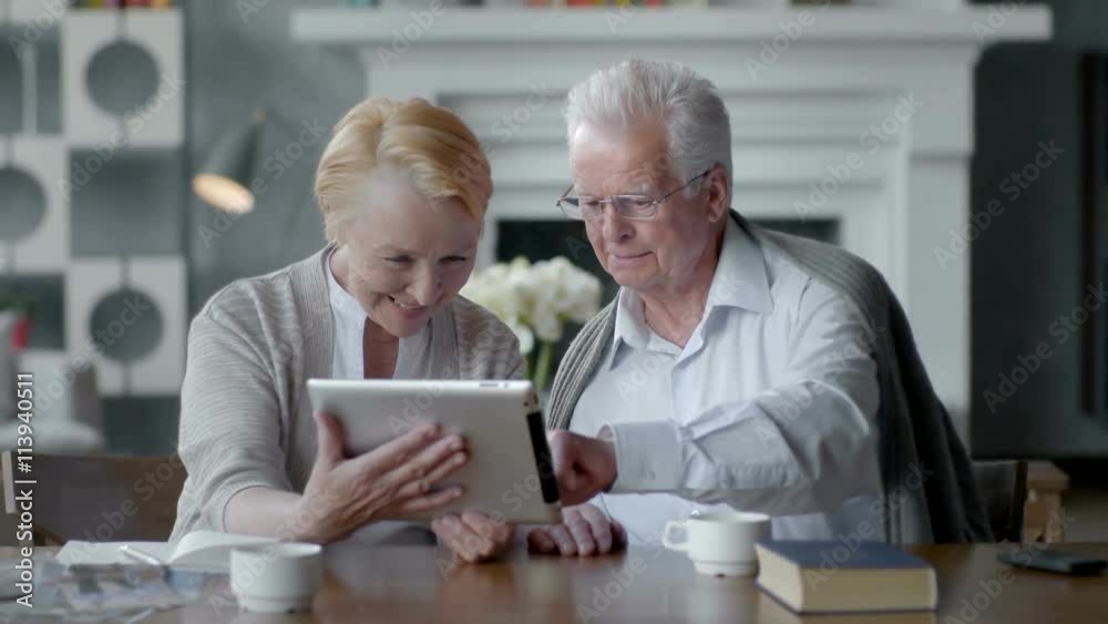 Happy lovely retired couple use tablet computer and laugh Happy lovely retired couple use tablet computer and laugh
