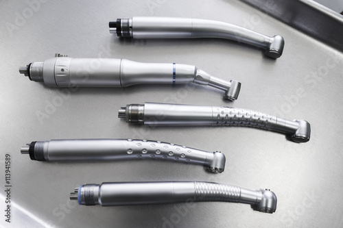 Set of dental turbine handpieces without burs flat lay. Top view on set of dental turbine handpieces on metal medical tray. photo