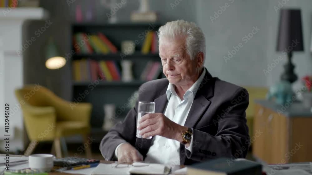 Unhappy sad and troubled elderly man incredulously looks at a pill and take it Unhappy sad and troubled elderly man incredulously looks at a pill and take it