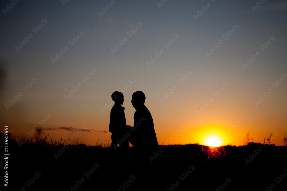 Silhouette of a man and his son with sunset background.  summertime