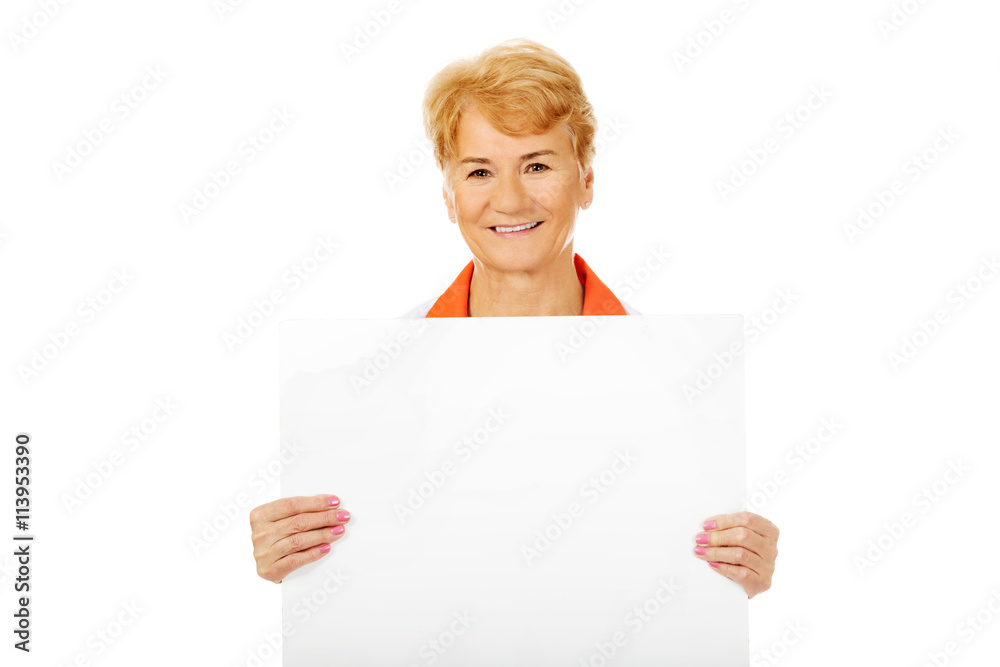 Smile elderly female doctor or nurse holding blank banner Smile elderly female doctor or nurse holding blank banner