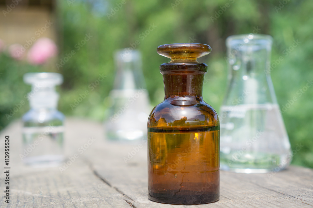 Liquid in chemical ware on a background of plants, fertilizers or pesticides in the garden. Liquid in chemical ware on a background of plants, fertilizers or pesticides in the garden.