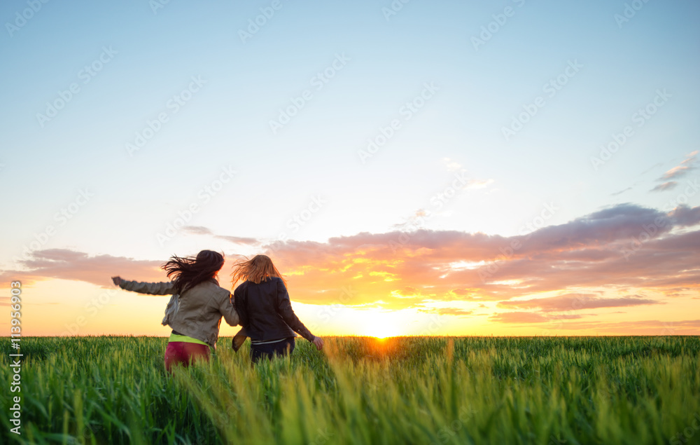 two girl friends running into wheat to the sunset two girl friends running into wheat to the sunset